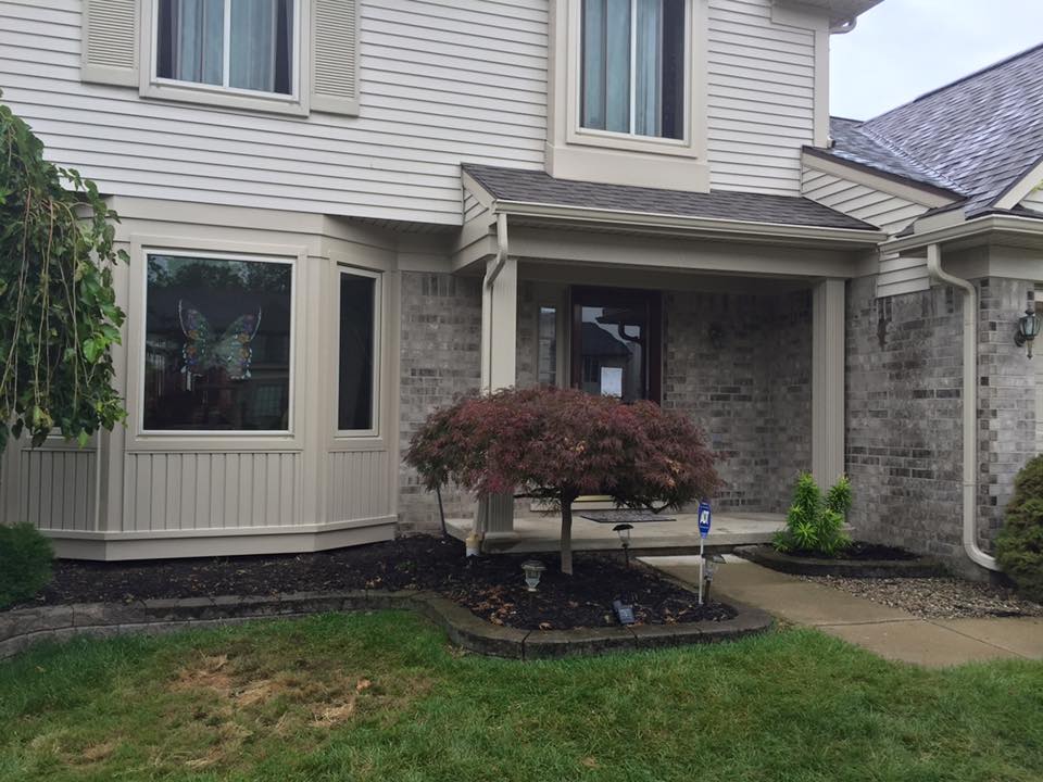 Exterior home with new siding, smiling homeowner.