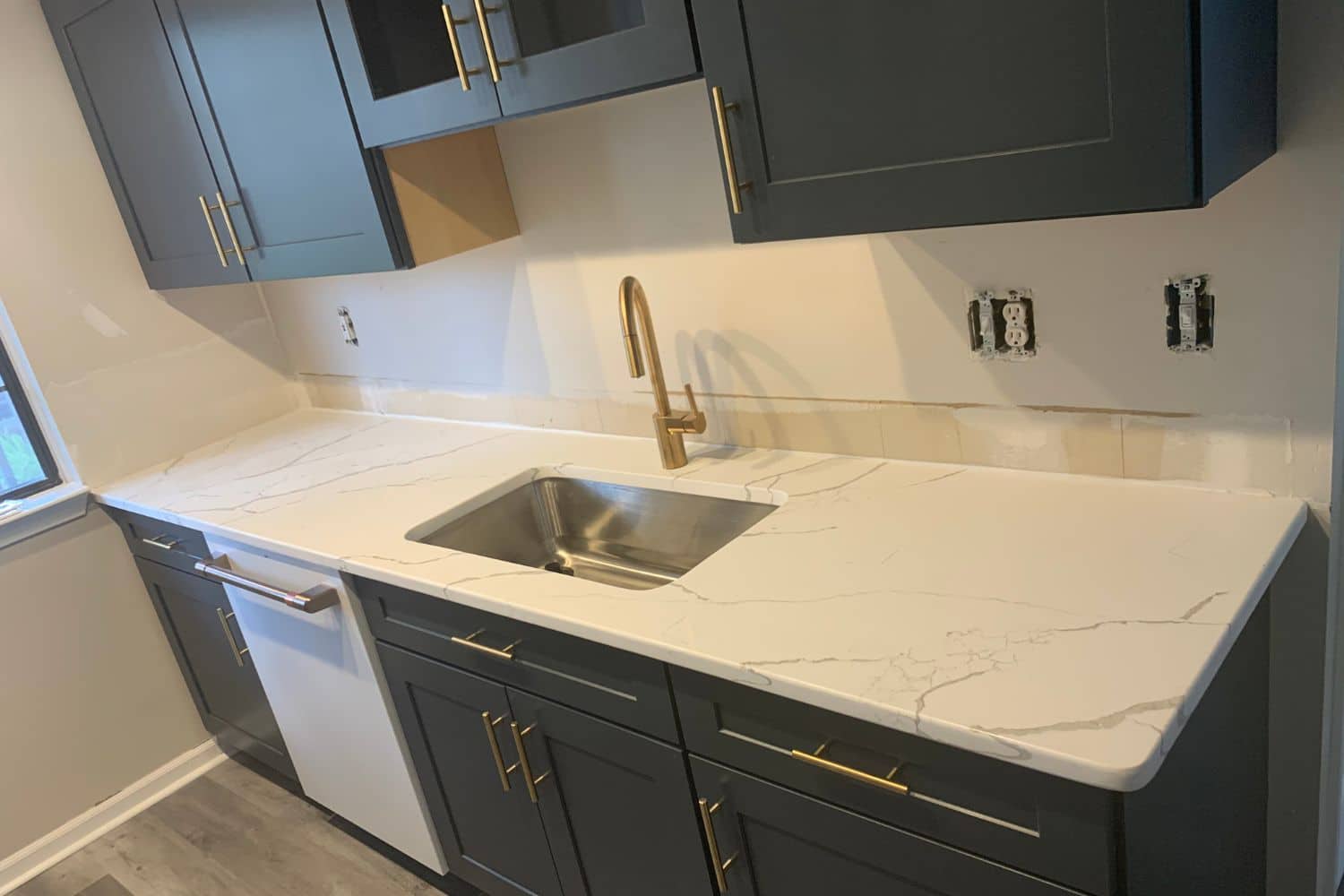 Kitchen remodel showing sink, cabinetry, and countertop installation requiring multiple trades