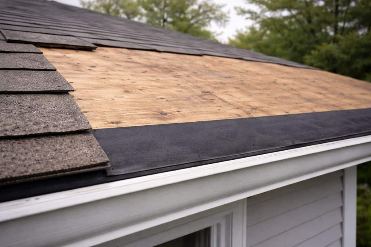 Roof tear-off replacement showing exposed wood decking and underlayment after old shingles were removed